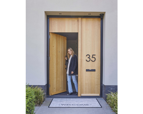 Een uitnodigende voordeur met huisnummer, brievenbus en deurmat met welkomstgroet