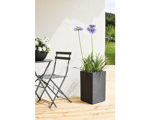 Arrangement met een tafel, een stoel en een rechthoekige plantenbak op een houten terras.