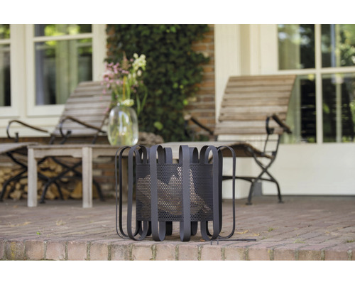 Metalen houtmand op een terras met tuinmeubelen op de achtergrond.