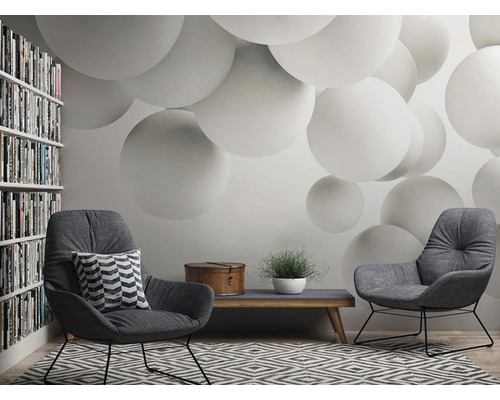 Woonkamer met twee fauteuils, een salontafel, een boekenkast en behang met bolmotief