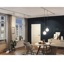 Woonkamer met railsysteem, spots, hanglampen, tafel, stoelen en dressoir.