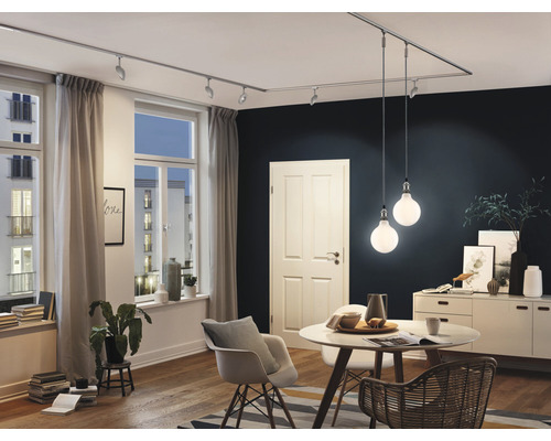 Woonkamer met railsysteem, spots, hanglampen, tafel, stoelen en dressoir.