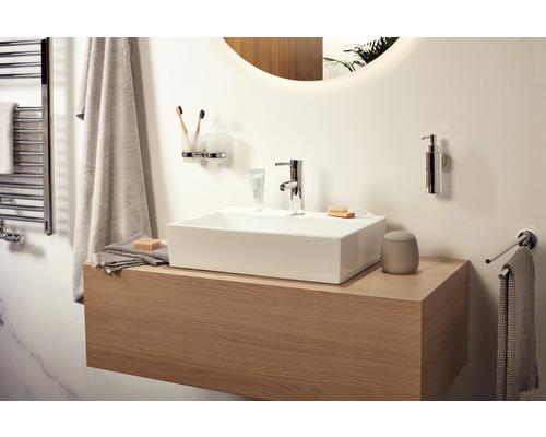 Lichte badkamer met wastafel, kraan, handdoeken en badkameraccessoires.