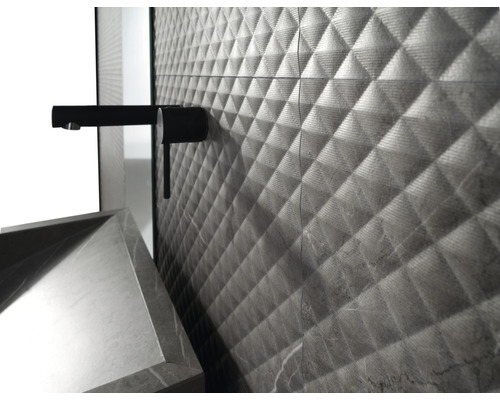 Close-up van een badkamer met wandtegels in ruitpatroon, kraan en wastafel