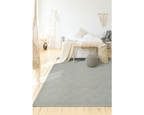 Grijs tapijt met geometrisch patroon in een slaapkamer met bed en houten vloer.