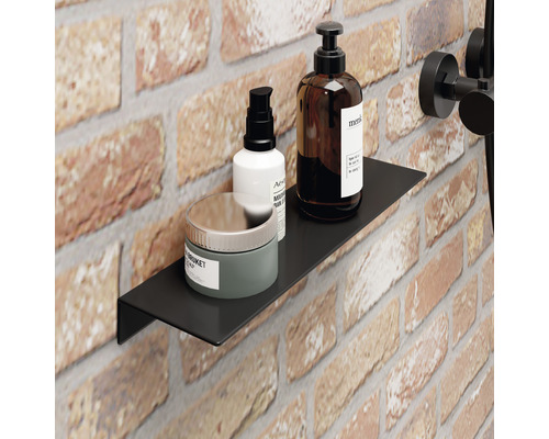Zwarte wandplank in de badkamer met verzorgingsproducten tegen een bakstenen achtergrond.