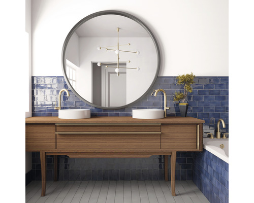 Badkamer met wastafel, ronde spiegels, kranen en blauwe tegels.