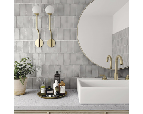 Moderne badkamer met grijze wandtegels, wastafel en ronde spiegel