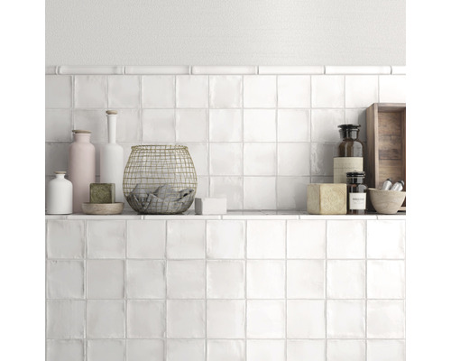 Wanddecoratie met witte vierkante tegels en plank met decoraties