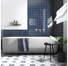 Moderne badkamer met bad, blauwe tegels en een vloer met patroon.