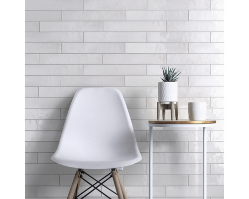 Lichte tegelwand met stoel en bijzettafel, moderne ruimte-indeling.