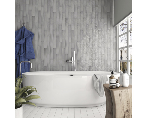 Badkamer met grijze tegels, bad, handdoek en decoratie