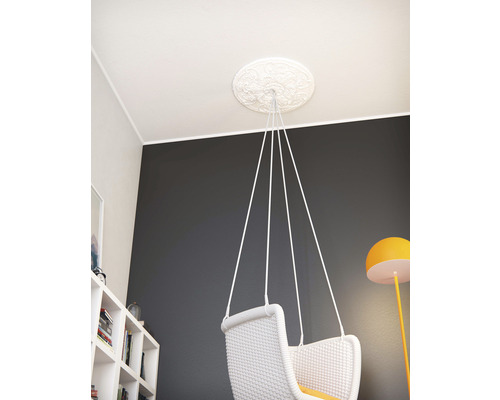 Plafondrozet met decoratief patroon en hangstoel in de kamer.