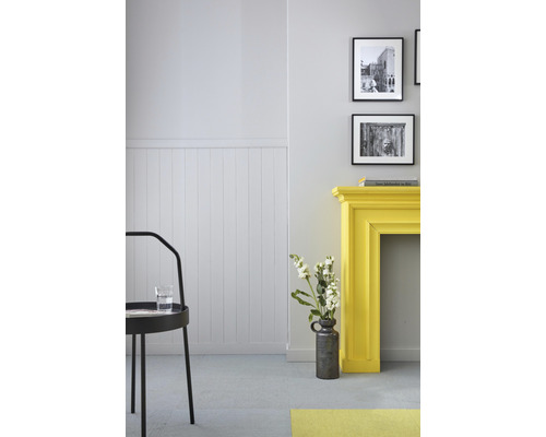 Lichte kamer met wandpanelen, een gele schouw, decoratie en een zwarte stoel.