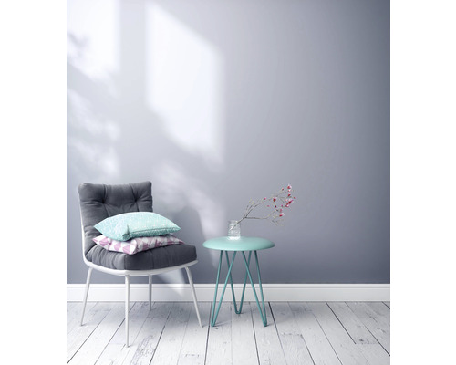 Scène met een stoel met kussens en een bijzettafel met bloemenvaas tegen een muur