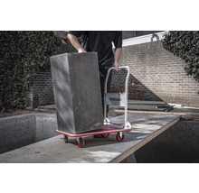 Man vervoert plantenbak met een transportroller in de tuin.