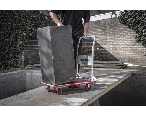 Man vervoert plantenbak met een transportroller in de tuin.