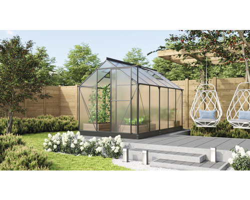 Kas in tuin met planten, houten schutting en hangstoel