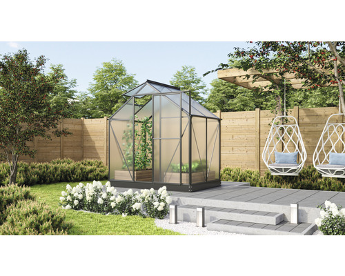 Kas in de tuin met planten en zitgelegenheid.