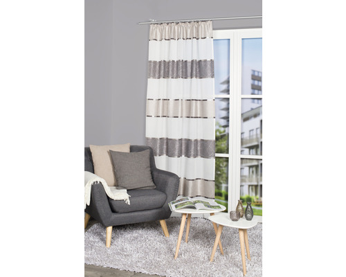 Woonkamer met fauteuil, tafel en gestreept gordijn