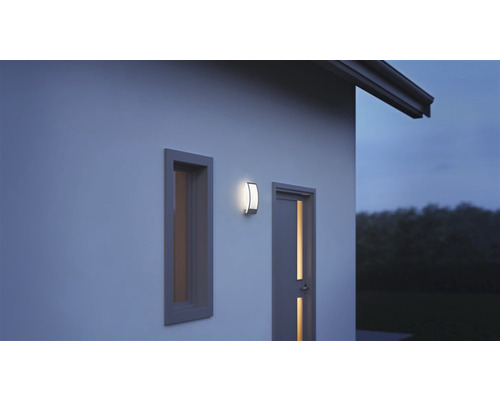 Gevel met raam, deur en een ingeschakelde buitenlamp.