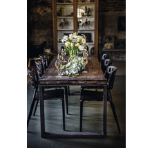 Eettafel met bloemstuk, glazen en zwarte stoelen in een kamer met vitrine