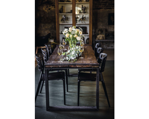 Eettafel met bloemstuk, glazen en zwarte stoelen in een kamer met vitrine