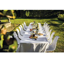 Gedekte lange tafel in de tuin met witte stoelen voor een feest