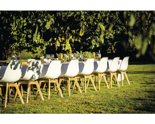 Scene van een gedekte tafel in de buitenlucht met witte stoelen op een gazon