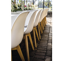 Rij eetkamerstoelen met houten poten aan een gedekte tafel