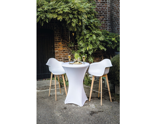 Sta-tafel met stretchhoes en barkrukken voor een bakstenen muur met begroeiing