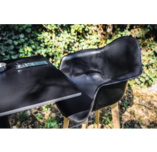 Zwarte tuinstoel en tafel met bestek buitenshuis.