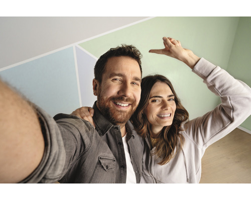 Een paar poseert voor een muur met geometrische patronen.