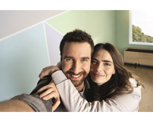 Gelukkig stel in een fris gerenoveerde, lichte kamer met gekleurde accenten op de muur