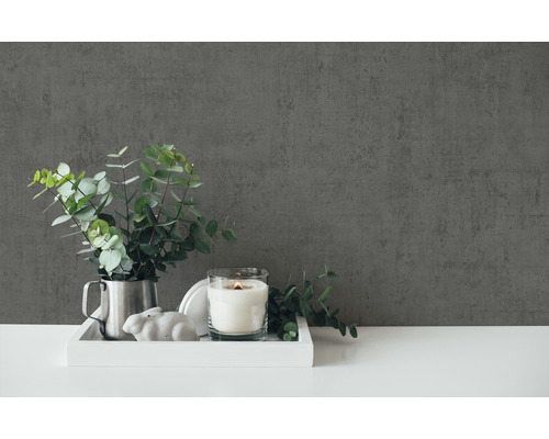 Decoratieve scène met kaars, plant en decoratief figuur op een dienblad voor een muur.