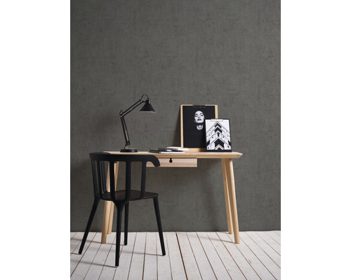 Bureau met lade, bureaulamp en zwarte stoel tegen een grijze muur