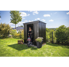 Tuinscene met metalen tuinhuis, vrouw met driewieler, bloembak en stapel hout