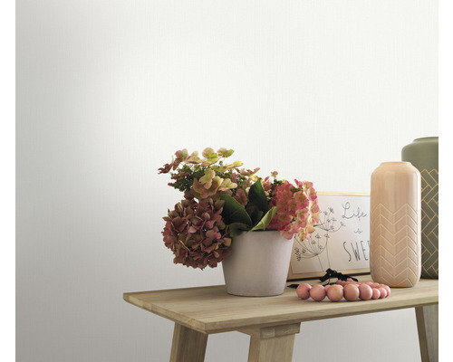 Close-up van een gedecoreerde houten tafel met bloemen, vazen en een fotolijst tegen een witte muur