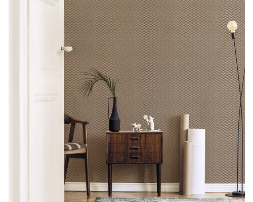 Woonkamer met patroonbehang, ladekast, stoel, staande lamp en decoraties.