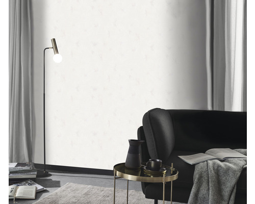 Woonkamer met vloerlamp, fauteuil, bijzettafel en wit behang