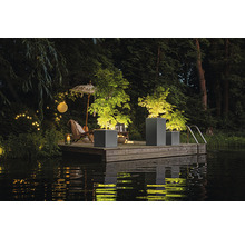 Scene met plantenbakken op een houten steiger aan het water, verlicht met lichtjes