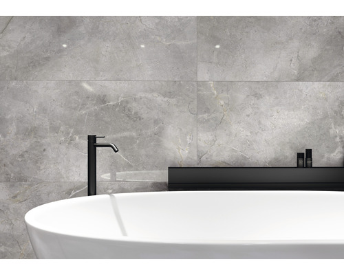 Moderne badkamer met grijze tegels, vrijstaand bad en zwarte kraan.