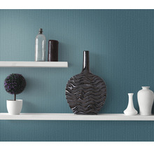 Decoratieve planken met vazen, een plant en een fles tegen een wand