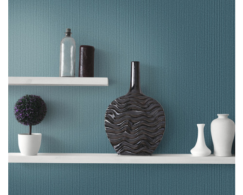 Decoratieve planken met vazen, een plant en een fles tegen een wand