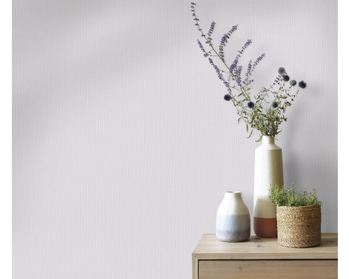 Wand met vliesbehang en bloemstukken in vazen op een houten kast