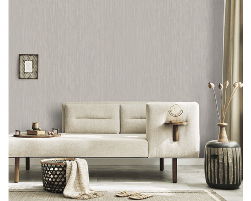 Woonkamer met lichtgrijs vliesbehang met lineair patroon, bank en decoratieve artikelen voor een gezellige sfeer.