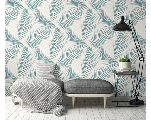 Woonkamer met palmbladbehang, hocker, lamp en bijzettafel voor een lichte sfeer