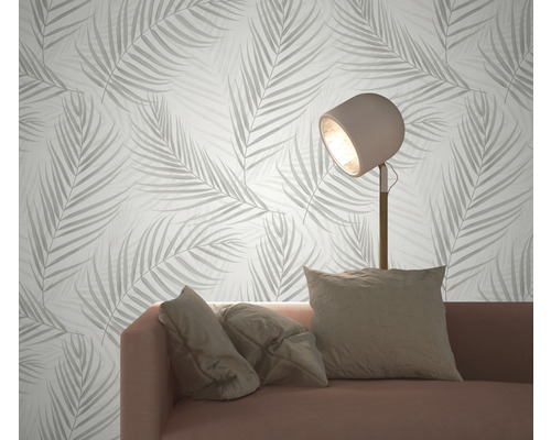 Woonkamer met bank, staande lamp en behang met bladerpatroon