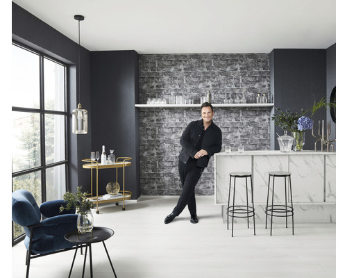 Lichte ruimte met bar, krukken, fauteuil, bijzettafel en een man