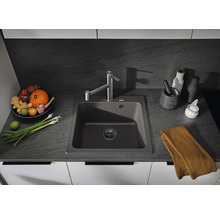 Spoelbak met kraan in een keukenomgeving met groenten en keukengerei